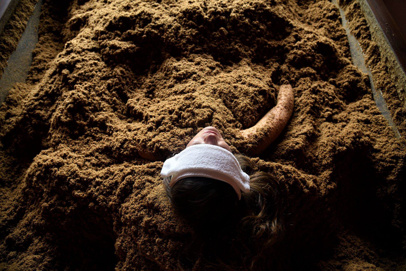 An image of a person taking a cedar enzyme bath in the mud