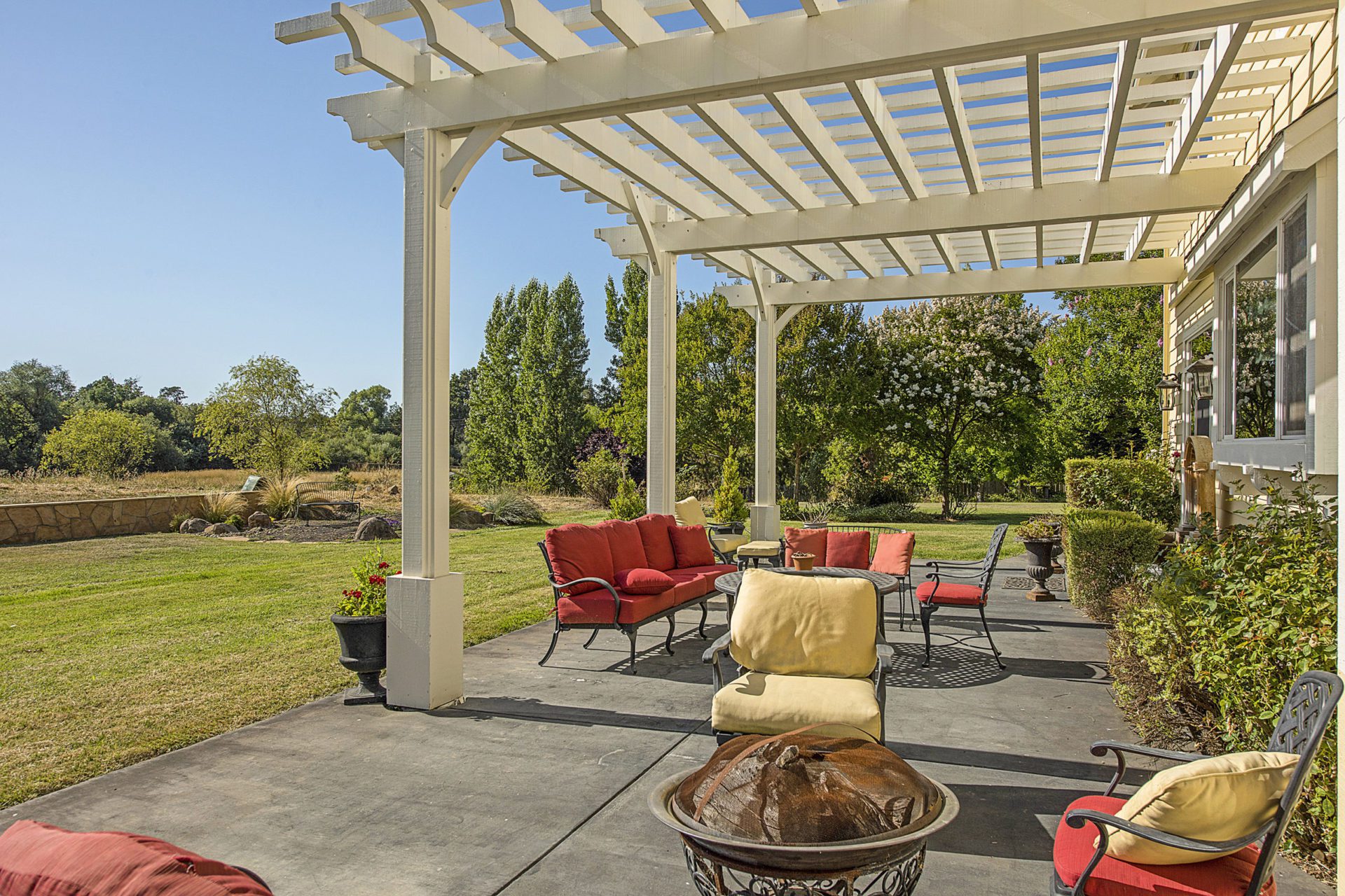 An image of house porch with lots of couches surrounded by greenery